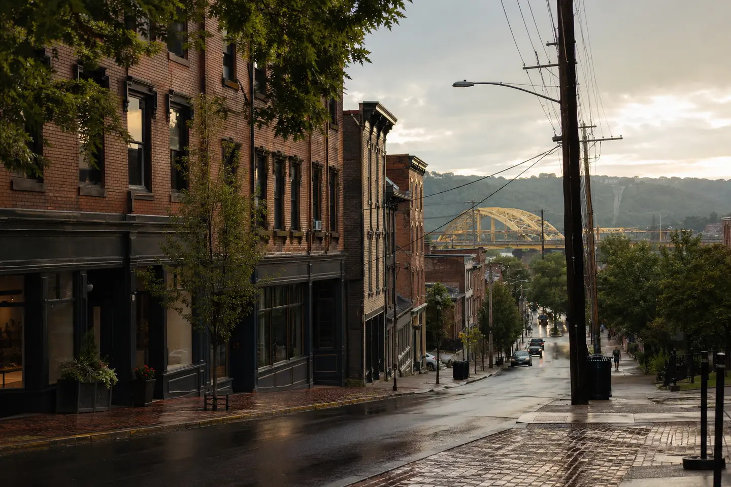 Wet street in Pittsburgh with brick buildings and yellow arched bridge in the background